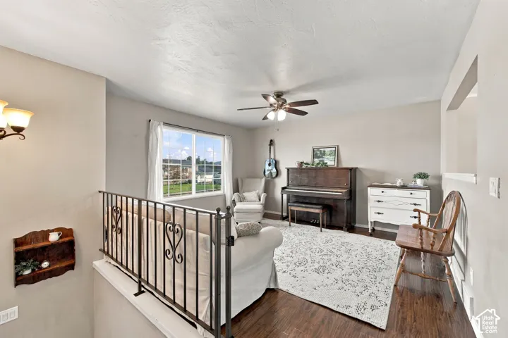 Open living area featuring wood-finish flooring, a ceiling fan with integrated lighting, and a large window