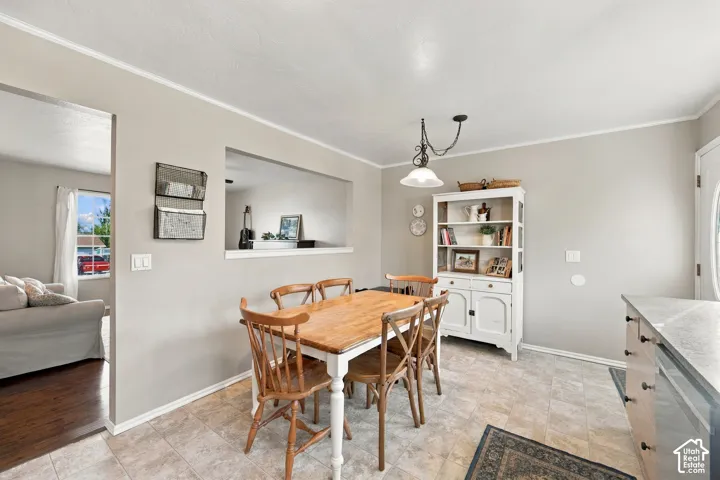 Tiled flooring, white painted walls, crown molding, a built-in display cabinet, and a pass-through opening to an additional room