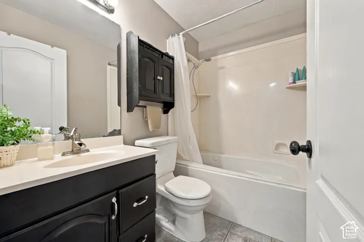 White bathtub with integrated shower, single vanity with a black cabinet, and a wall-mounted storage cabinet