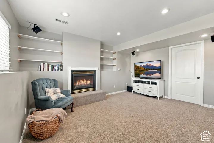 Recessed lighting, built-in shelving, carpet flooring, fireplace with white surround, and white interior door
