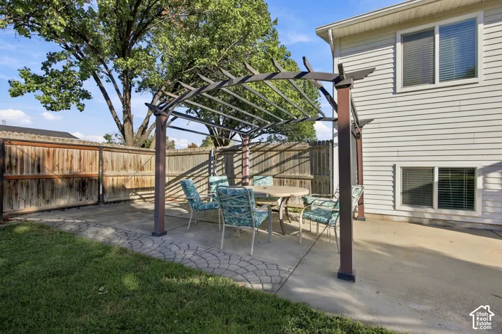 Concrete patio featuring a pergola structure and privacy fencing