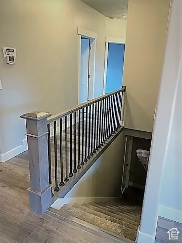 Modern staircase with wood-finish treads and metal spindle railing, leading to upper-level landing