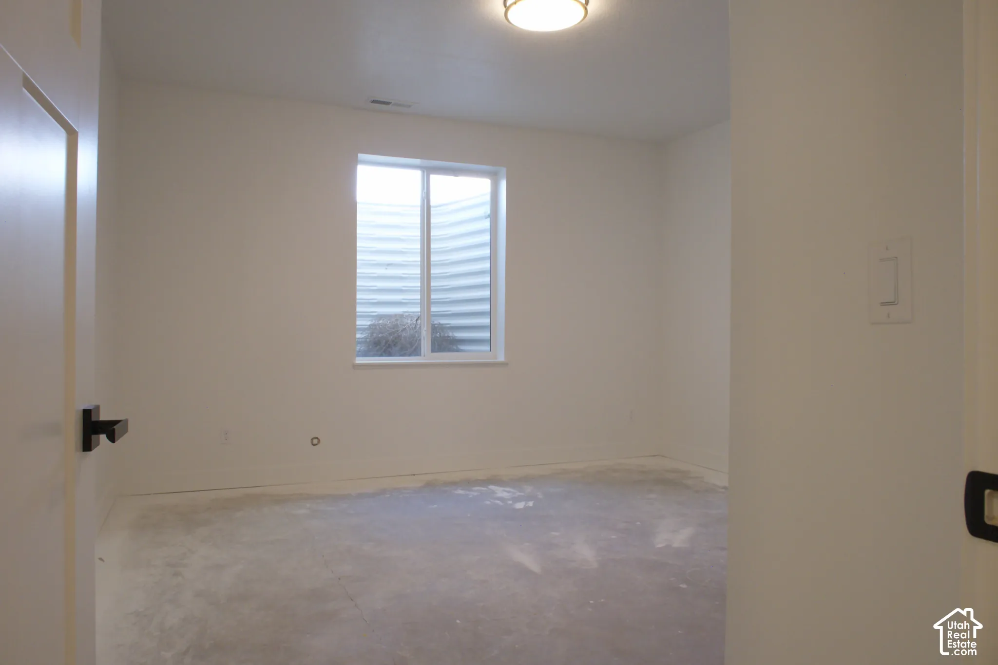 Recessed window with a window well, overhead flush mount light fixture, and light-toned walls