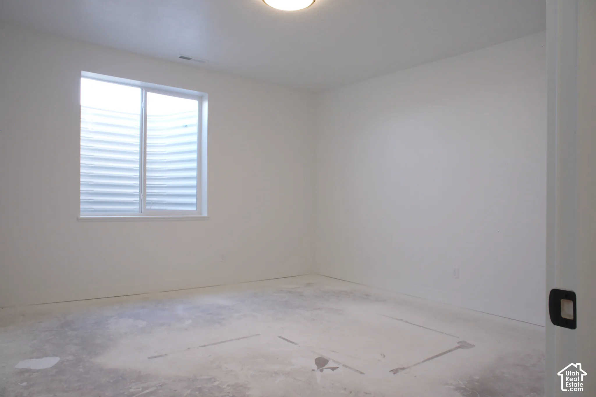 Single window with white frame, white painted walls, and overhead flush-mount lighting fixture