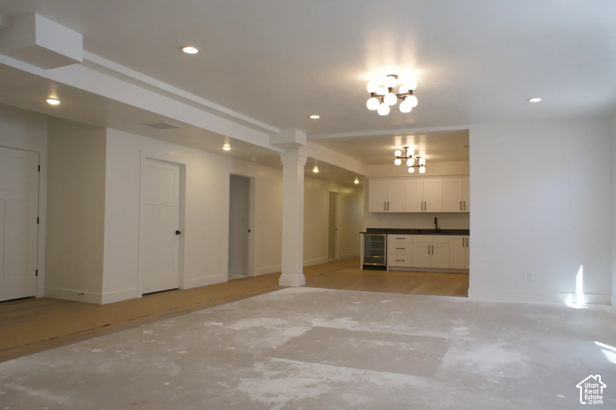 Recessed lighting, modern ceiling light fixtures, white flat-panel cabinetry, dark countertops, and a beverage refrigerator