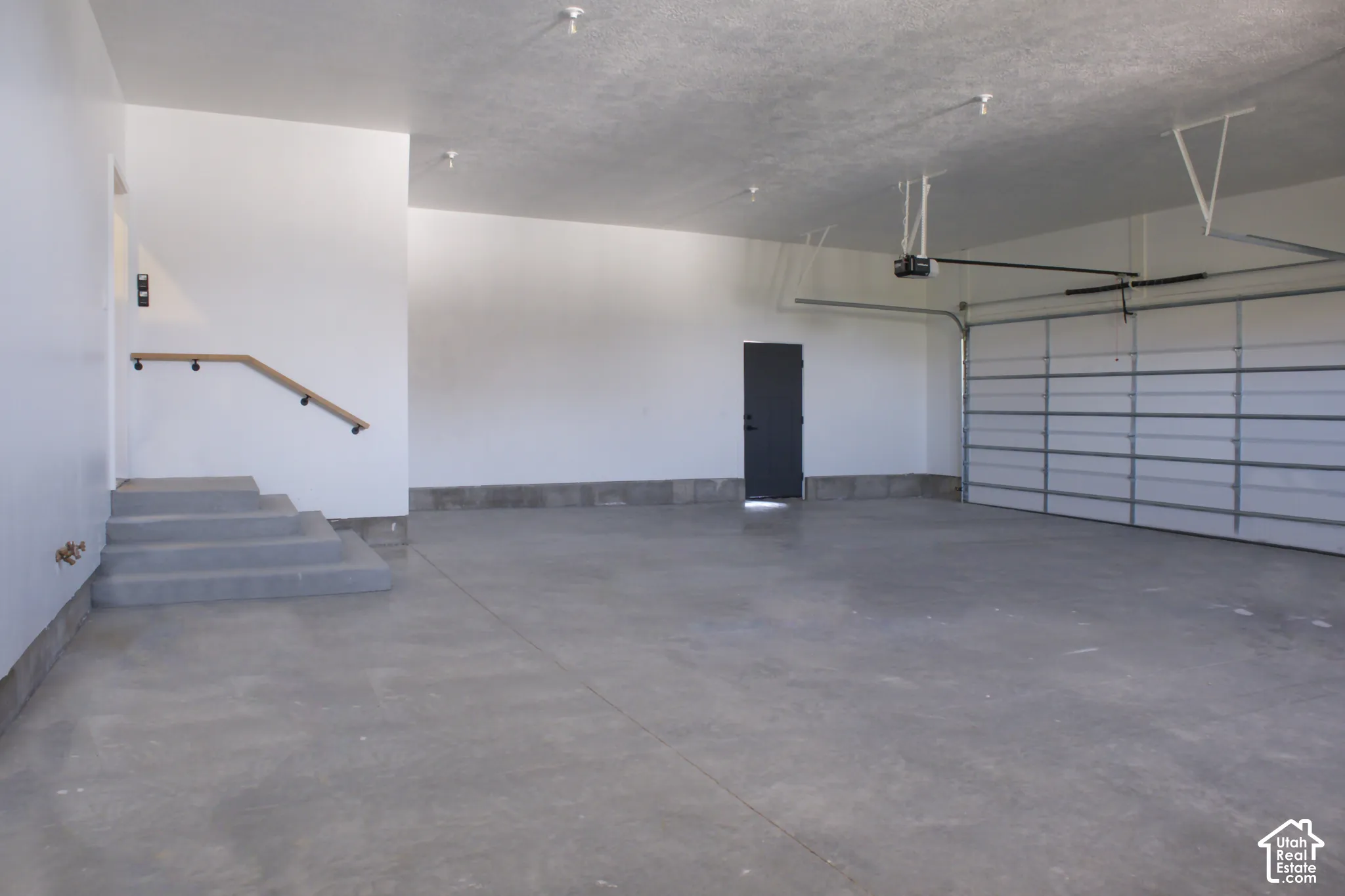 Spacious garage featuring a concrete floor, overhead lighting, and an automatic garage door opener