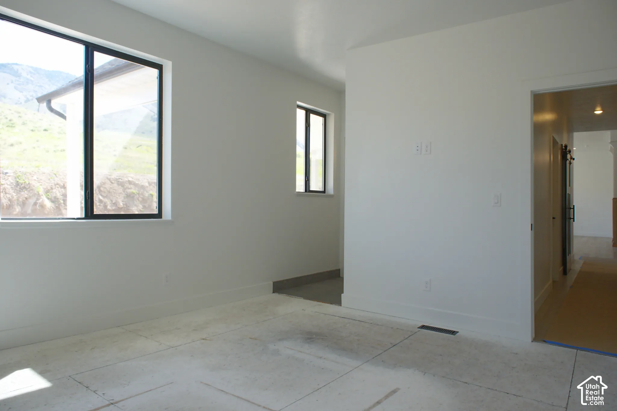 Two windows with black frames, white walls, and a doorway with a dark barn door
