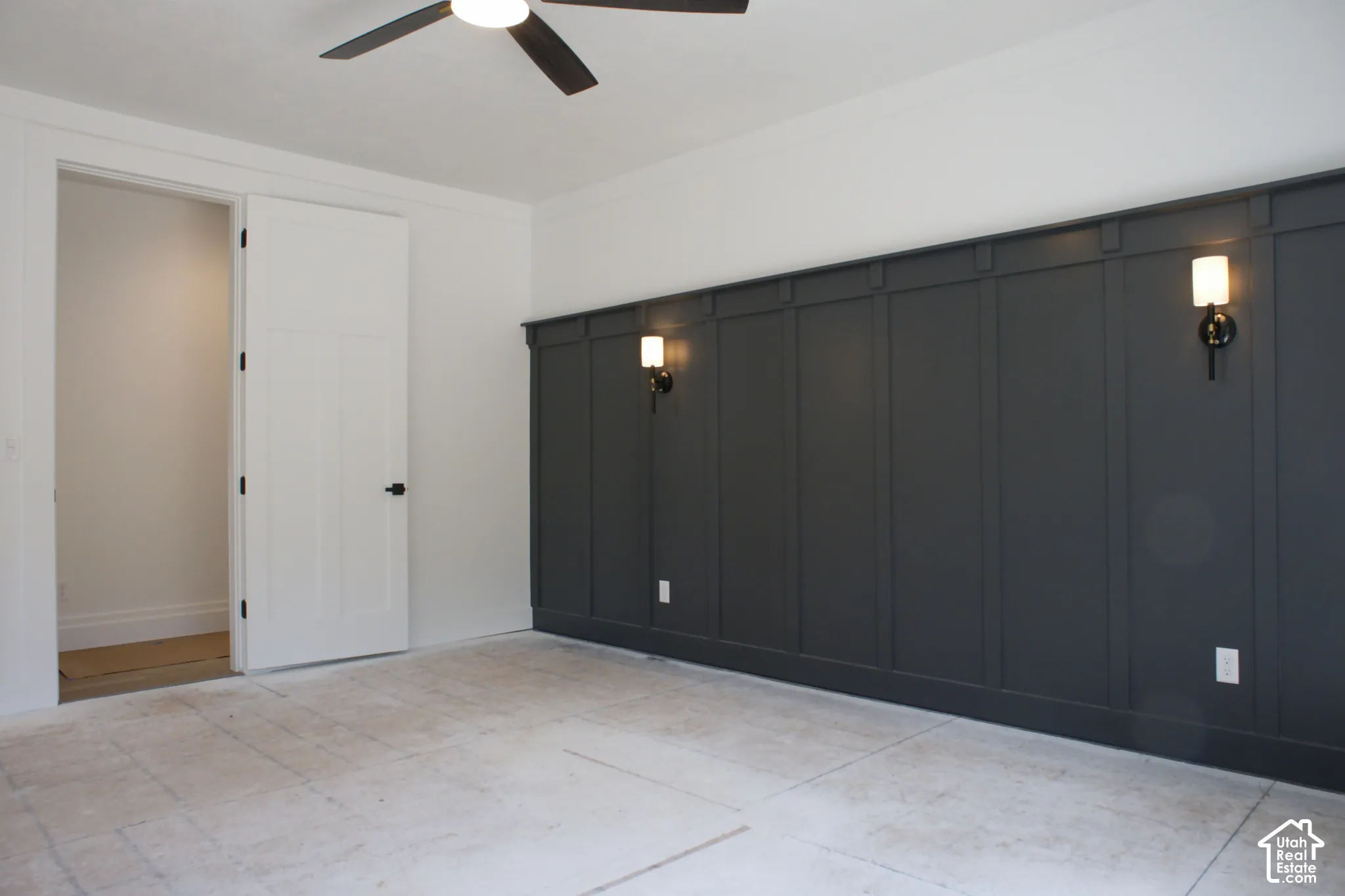 Board and batten accent wall with integrated sconces, ceiling fan with light, and white paneled door