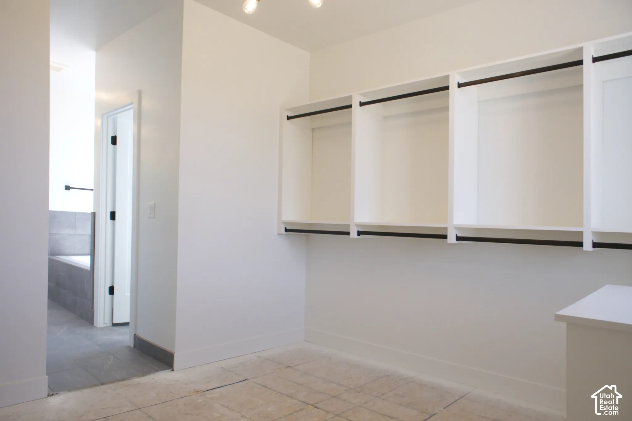 Spacious walk-in closet featuring built-in shelving with white frame detailing and dark accent rails, tile flooring, and recessed ceiling lighting
