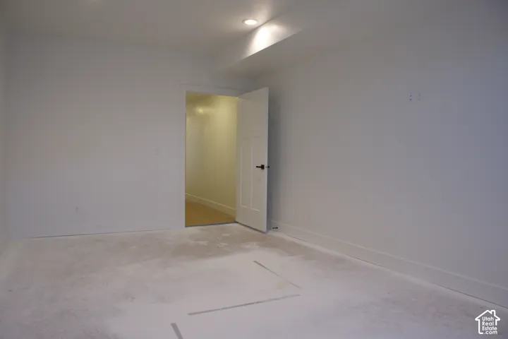 Recessed ceiling lighting, white interior door with dark hardware, and white baseboards