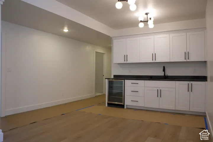 Contemporary wet bar featuring white cabinetry, dark countertops, an undermount sink with a matte black faucet, and a built-in beverage refrigerator