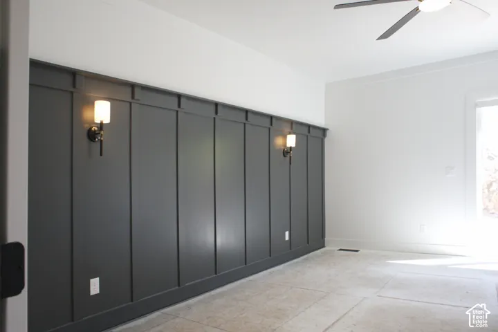 Accent wall with board and batten detailing, equipped with two wall sconces and a ceiling fan