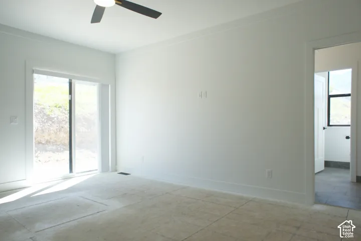 Spacious room featuring a ceiling fan, sliding glass door, and neutral wall tones