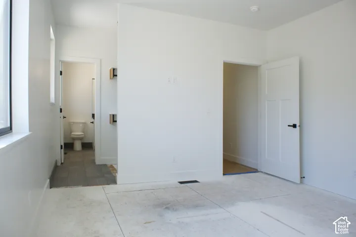 White interior walls, black-framed window, matte black door hardware, white panel door, and gray tile flooring in the adjacent space