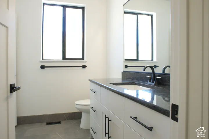 White vanity with black hardware, dark countertop, and black faucet
