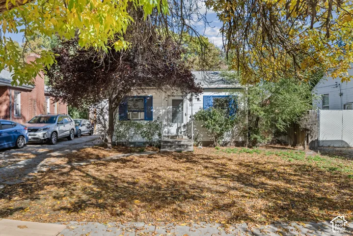 Single-story exterior featuring white siding, blue shutters, a central entrance, and a concrete driveway