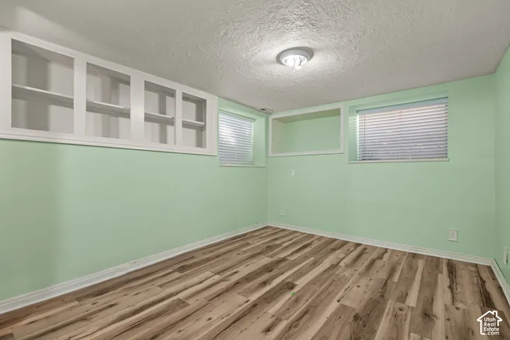 Interior room featuring wood-finish flooring, built-in recessed cabinetry, and dual windows with fitted blinds