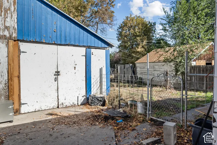 Detached outbuilding with double doors, concrete ground surface, and perimeter wire fencing