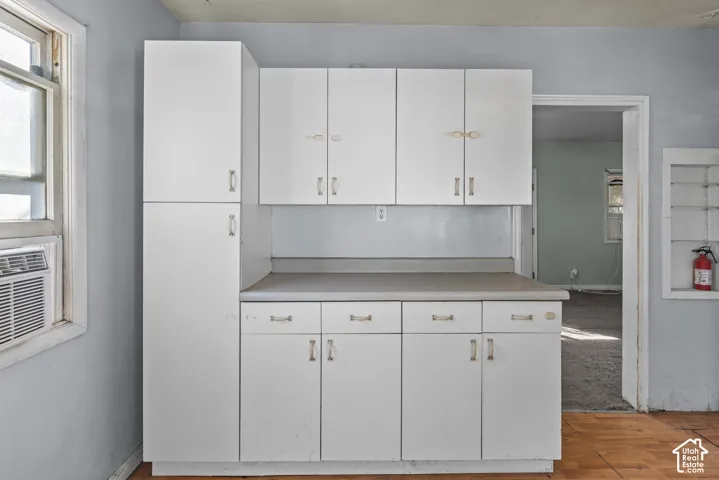 White cabinetry featuring a floor-to-ceiling pantry unit, neutral-toned countertops, and a built-in recessed wall shelving unit