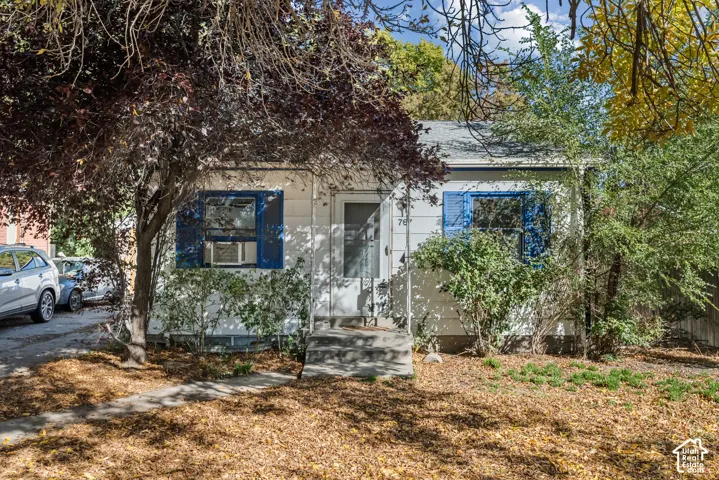 Single-story exterior featuring white siding, blue shutters, a concrete front stoop, and a concrete pathway