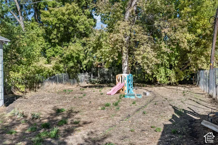 Expansive backyard featuring mature trees and perimeter chain-link fencing