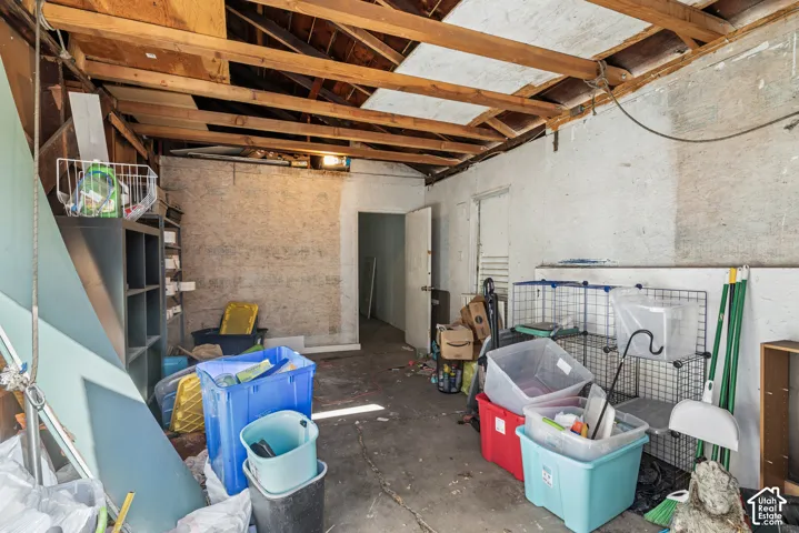 Detached structure featuring an exposed timber ceiling, concrete flooring, and a single-swing interior door