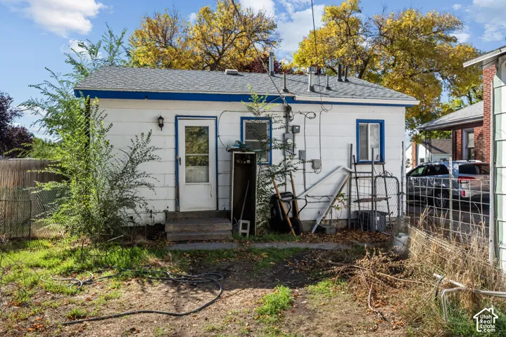 Concrete block exterior featuring a shingle roof and a central entry door with concrete steps