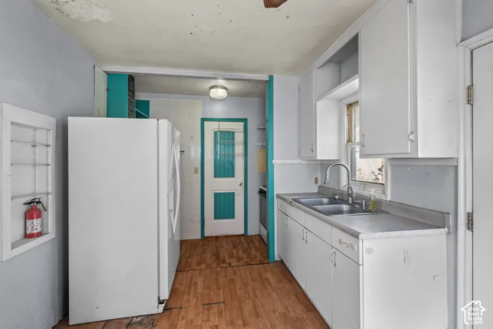Kitchen featuring wood-finish flooring, white cabinetry, a dual-basin stainless steel sink with a goose-neck faucet, and a built-in wall niche