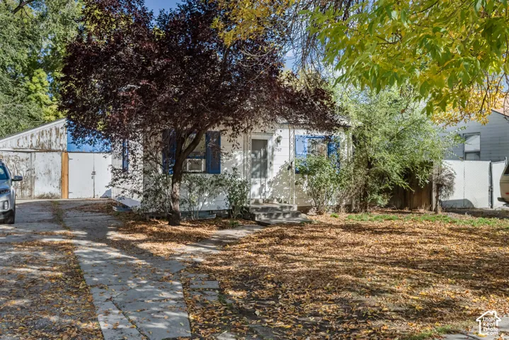 Single-story exterior featuring light-toned siding, blue window shutters, concrete walkway, and detached garage