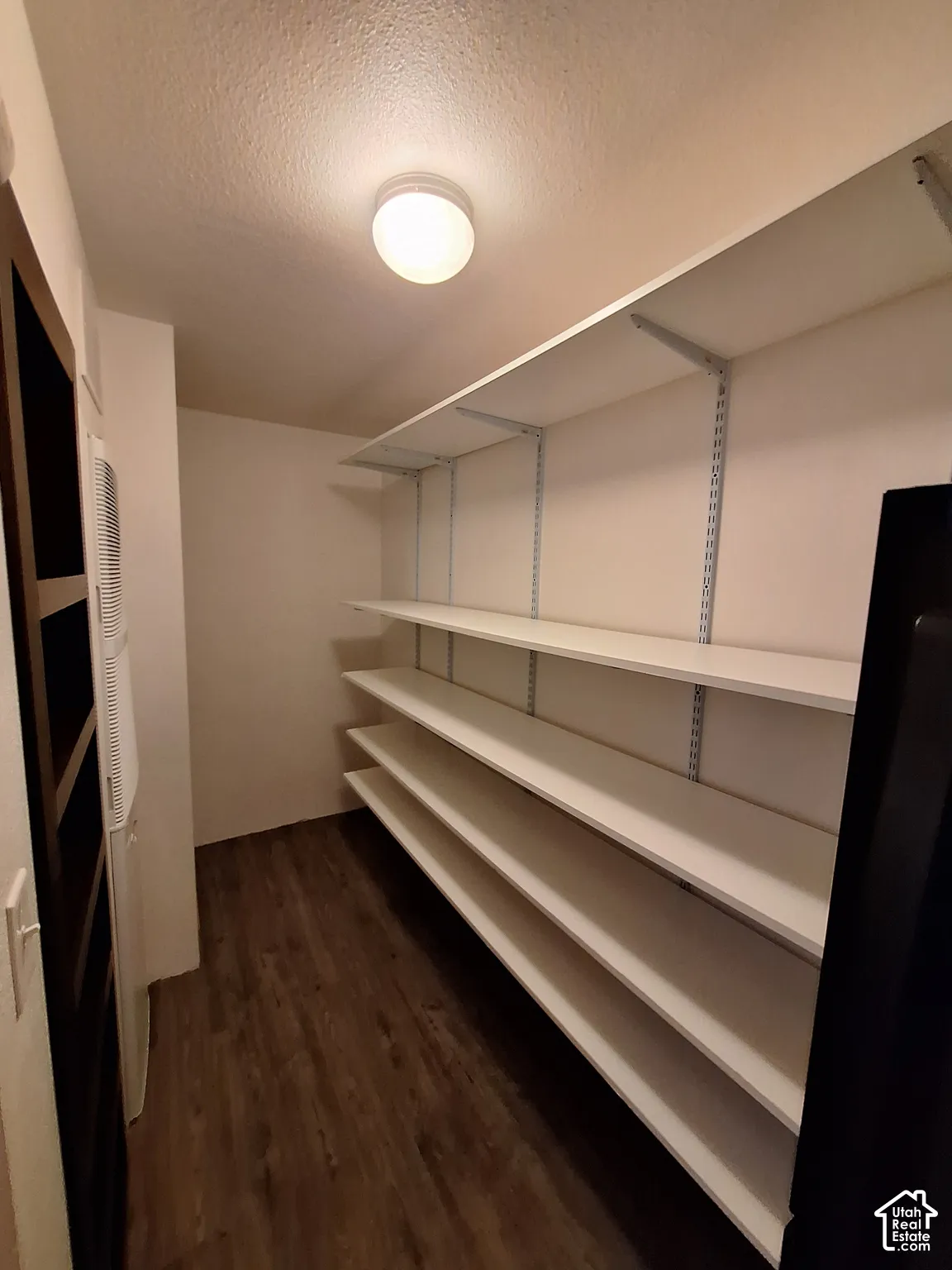 Recessed ceiling lighting, wood-finish flooring, and multiple white shelving units