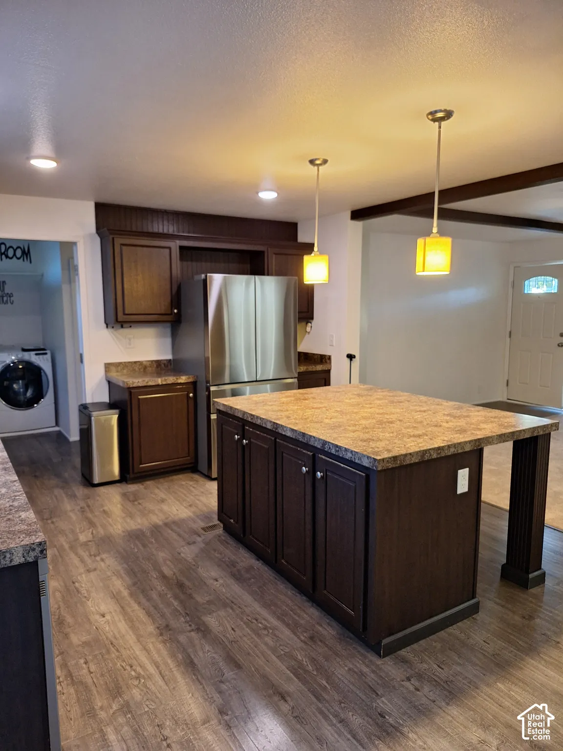 Kitchen featuring dark wood-finish cabinetry, a large center island with a stone-look countertop, wood-finish flooring, and recessed ceiling lights