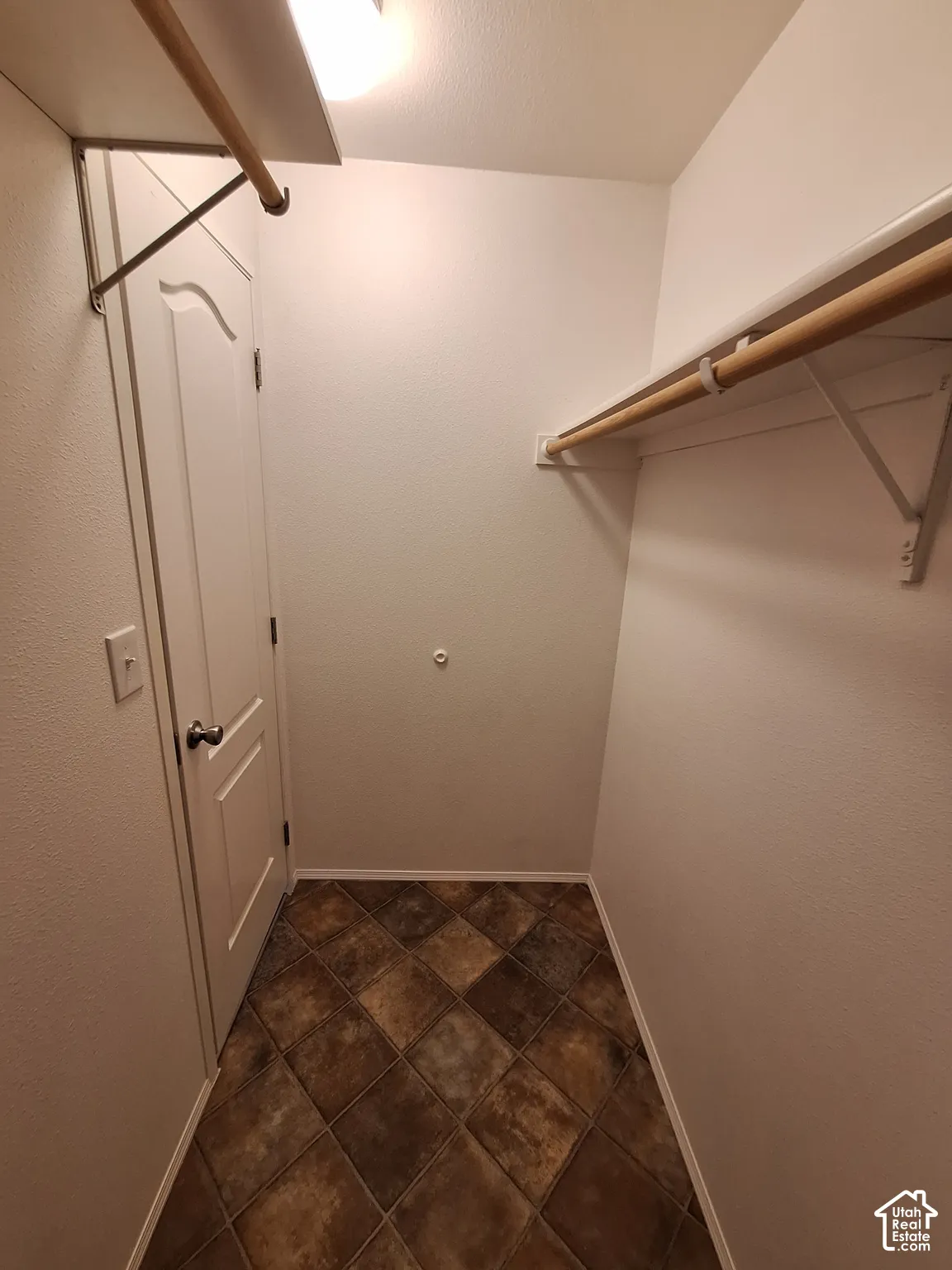 Tiled flooring, built-in shelving, and hanging rods