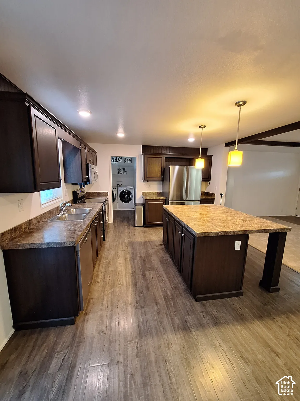 Spacious kitchen with a central island, dark wood-finish cabinetry, stone-finish countertops, and wood-finish flooring