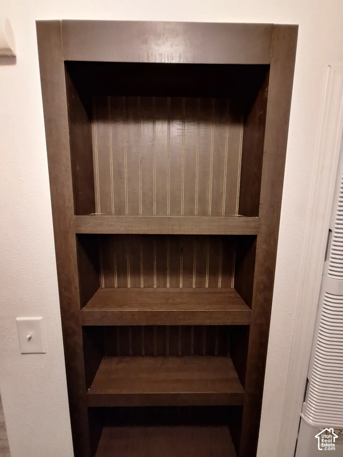 Built-in dark wood shelving unit with three levels and a beadboard back panel