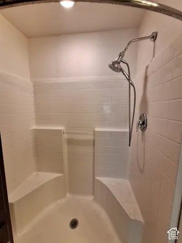 Tiled shower enclosure featuring integrated seating, a handheld shower fixture, and a built-in shelf