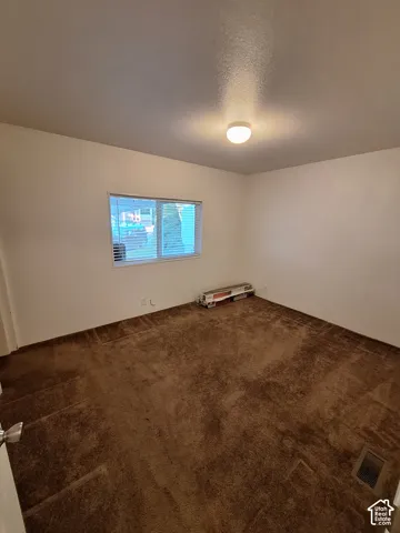 Window with horizontal blinds and ceiling-mounted light fixture in a carpeted room