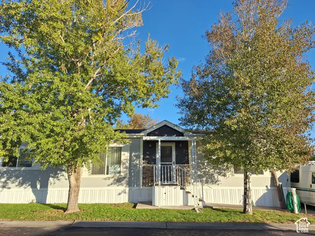 Residence featuring a covered porch with white railings, light-colored siding, and a dark contrasting entrance facade