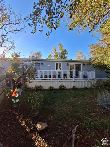 Rear exterior with a spacious deck, white railing, and dual sliding glass doors