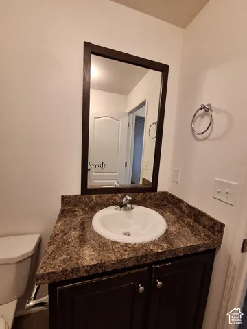 Bathroom vanity with a dark wood-finish cabinet, a brown and black patterned countertop, and a white oval sink with a chrome faucet