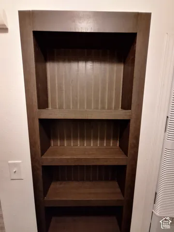 Built-in dark wood shelving unit with three levels and a beadboard back panel