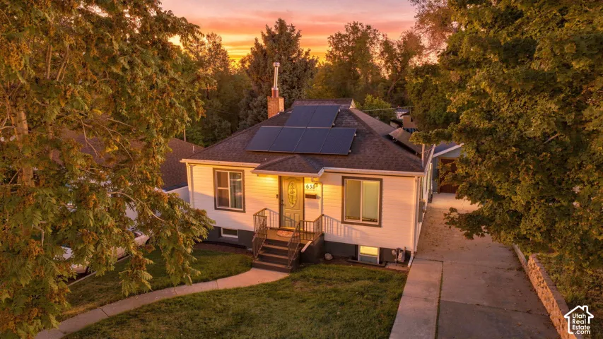 Front exterior featuring a gabled roof, solar panels, and a concrete driveway