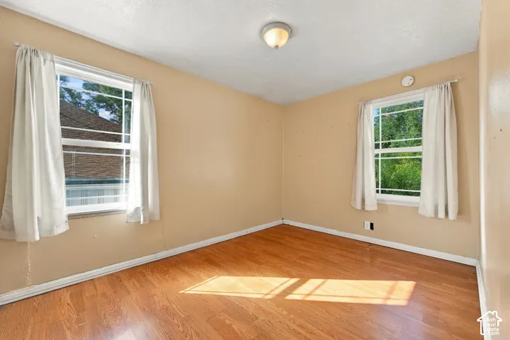 Wood-finish flooring, two windows, and a flush mount ceiling light fixture