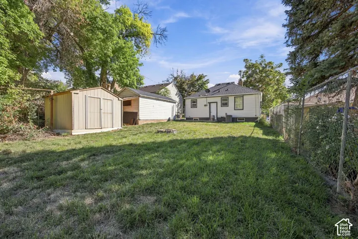 Expansive backyard featuring a detached storage shed, a detached garage structure, and a chain-link fence perimeter