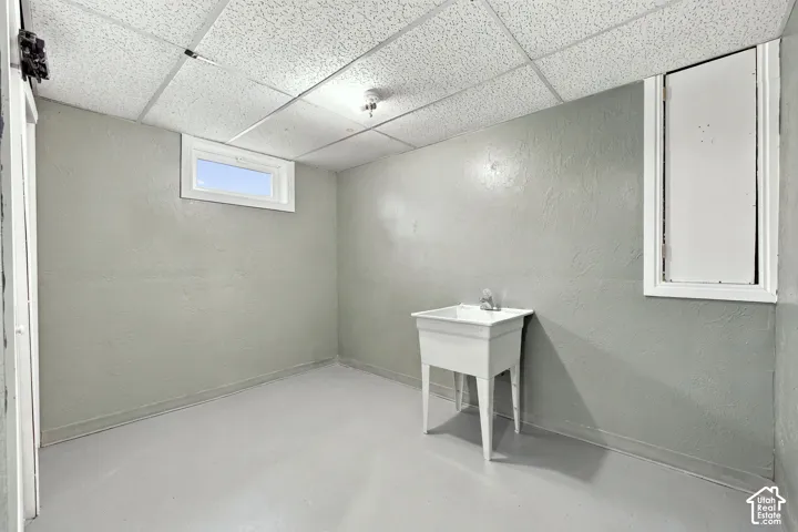 Utility room featuring a drop ceiling, painted concrete floor, and a utility sink