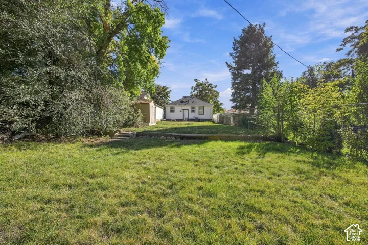 Expansive backyard featuring a large grassy area, mature trees, and a storage shed