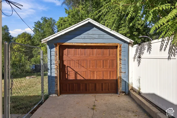 Detached auxiliary structure featuring wood-paneled garage door, blue exterior siding, and white trim