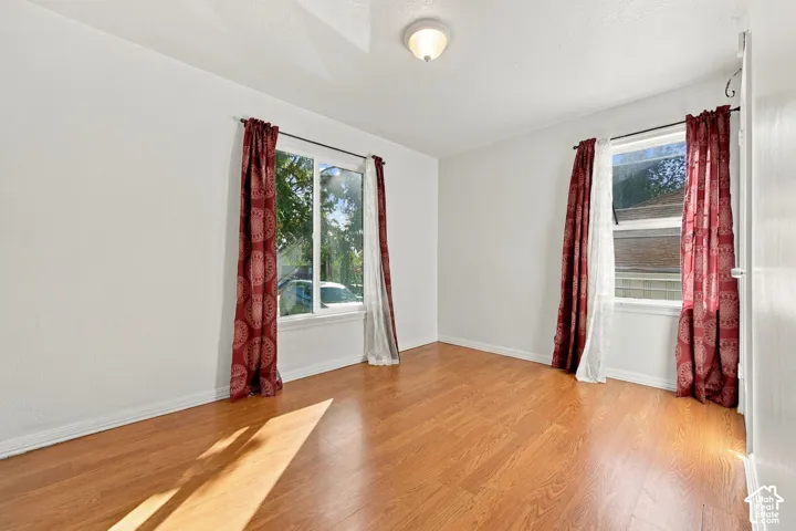 Wood-finish flooring throughout, bright white walls, two windows with white trim, and a ceiling-mounted light fixture
