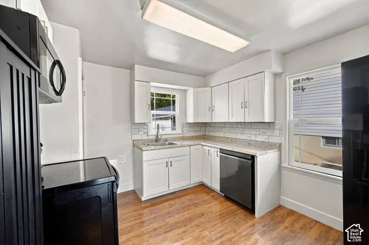 Kitchen featuring wood-finish flooring, white cabinetry, a subway tile backsplash, and light-toned countertops