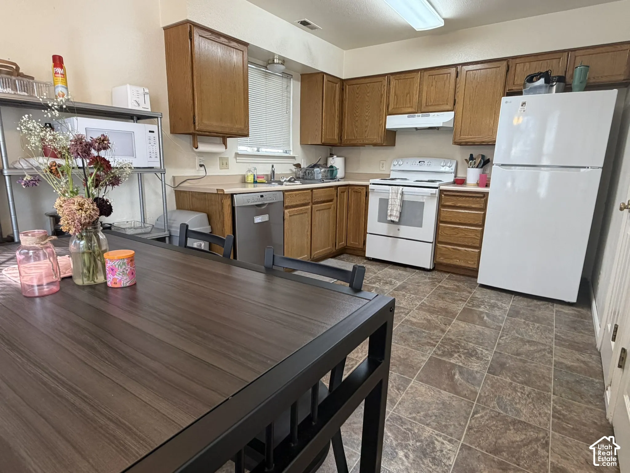 Kitchen featuring wood-finish cabinetry, white appliances, and a light-toned countertop