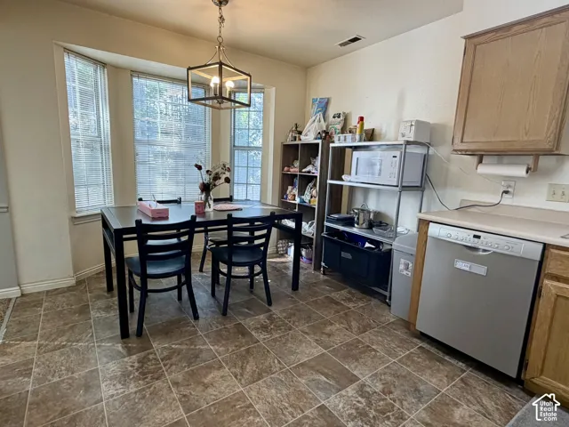 Bay window, tile flooring, stainless steel dishwasher, light wood finish cabinetry, and an attached light fixture